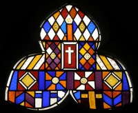 A window with a wonderful pattern, and the theme of the cross, in blue, orange, yellow, red and white